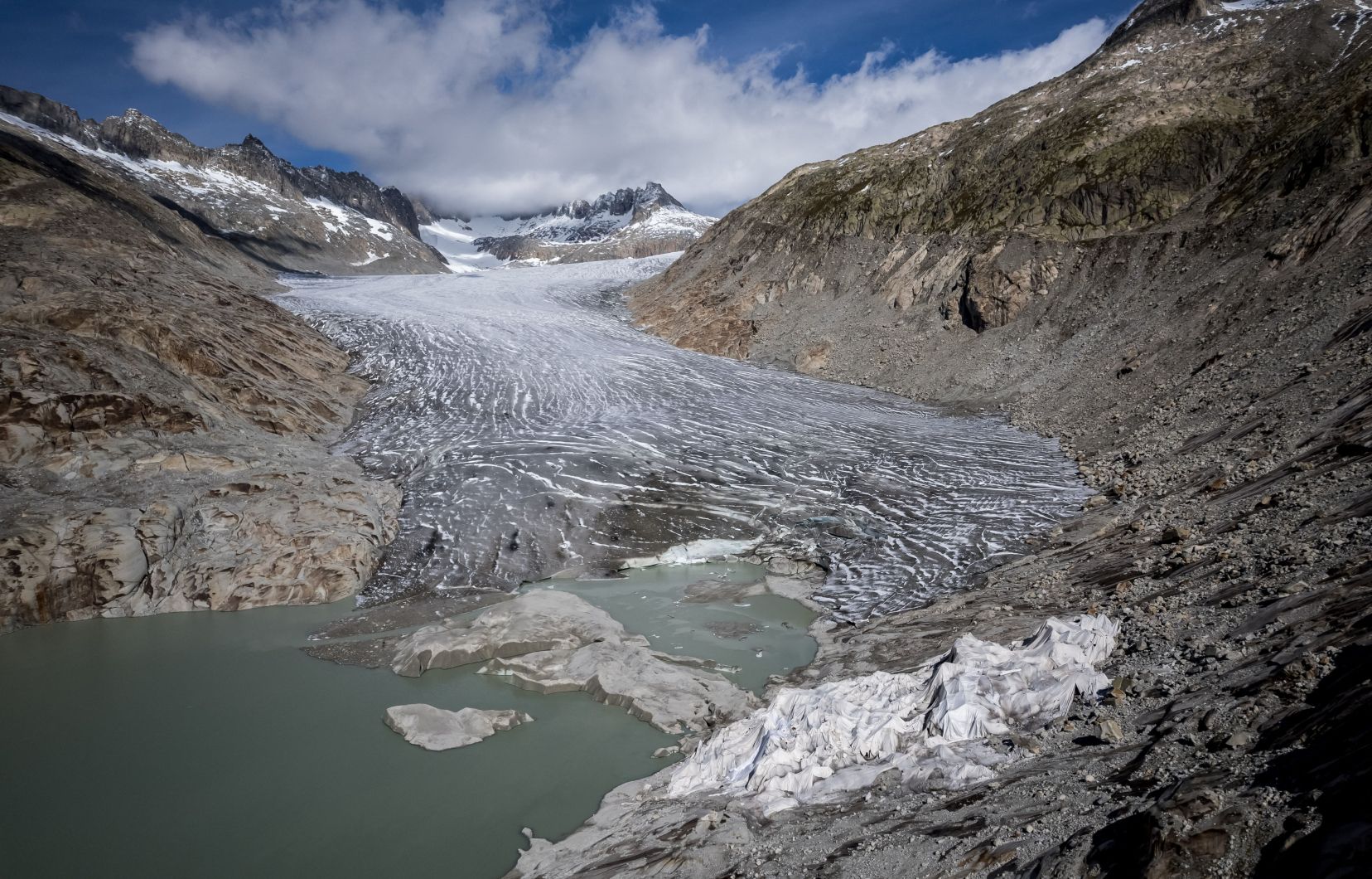 Photo aérienne du glacier du Rhône dont une petite partie est recouverte de mousse isolante pour l’empêcher de fondre, à côté de son lac glaciaire formé par la fonte du glacier due au réchauffement climatique, dans les Alpes suisses, le 30 septembre 2024.
