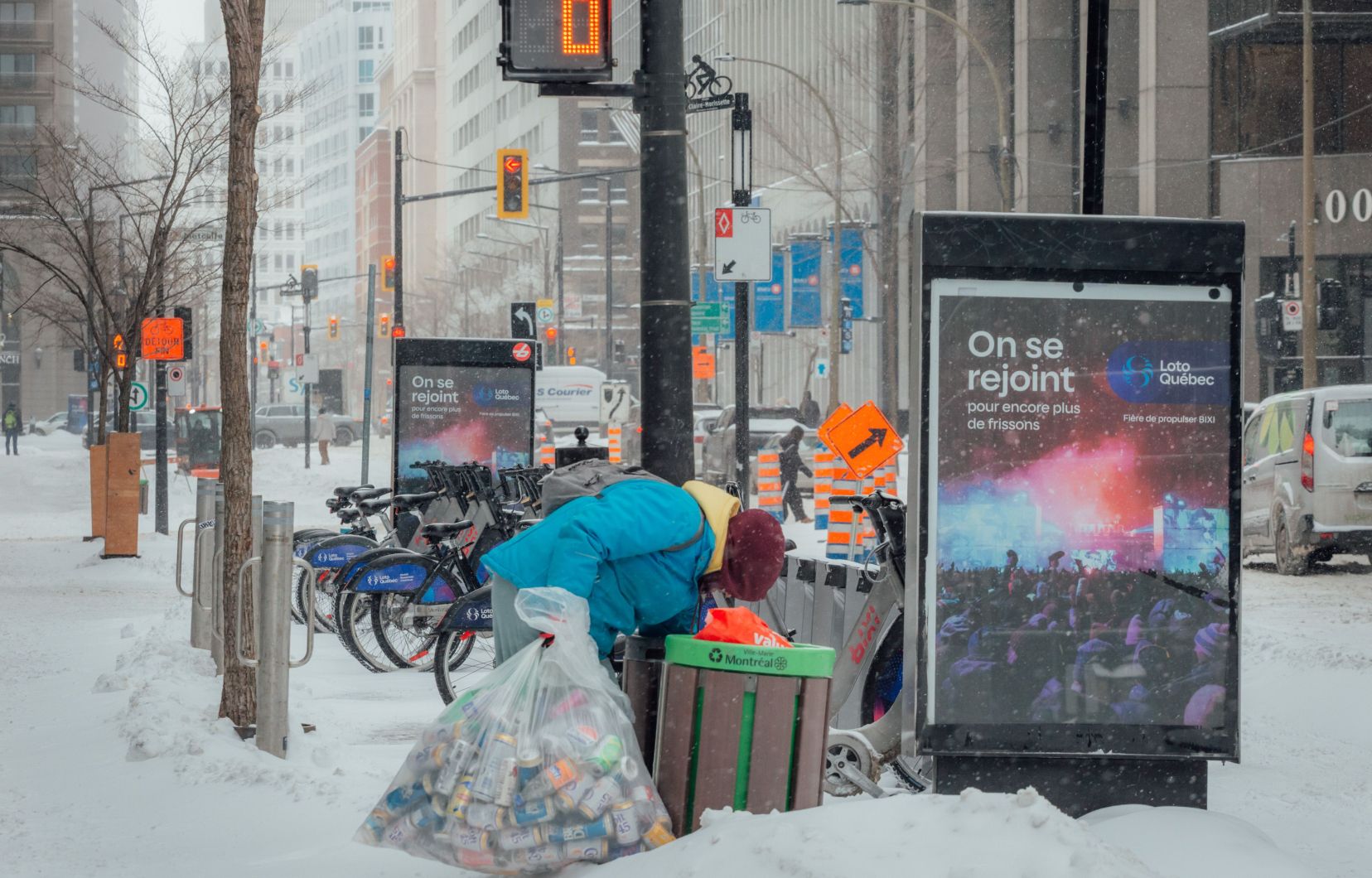 Une femme ramassant des canettes dans une poubelle sur le boulevard René-Lévesque, à Montréal