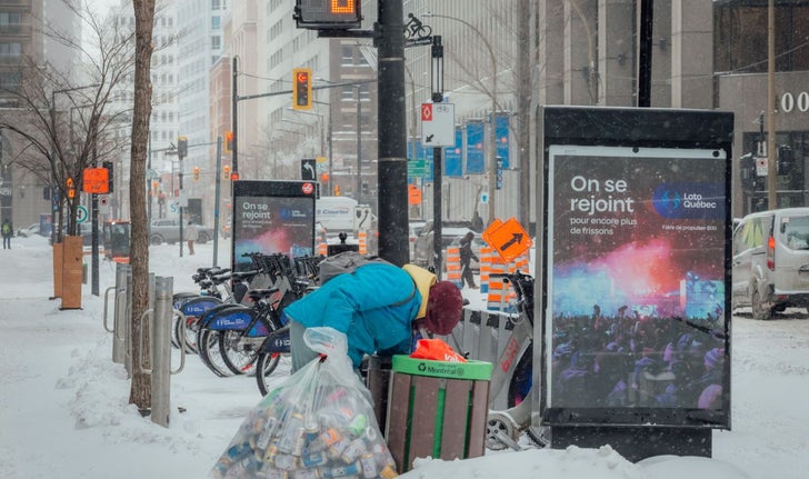 Une femme ramassant des canettes dans une poubelle sur le boulevard René-Lévesque, à Montréal